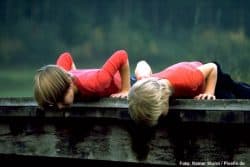 Zwei Kinder schauen von einer Brücke herunter.